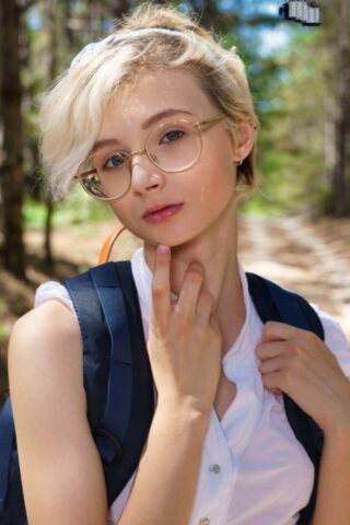 Young looking girl Azshara strips off school clothes on a dirt road in woods